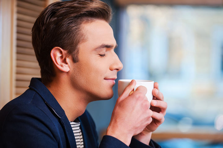 A man smelling a cup of coffee