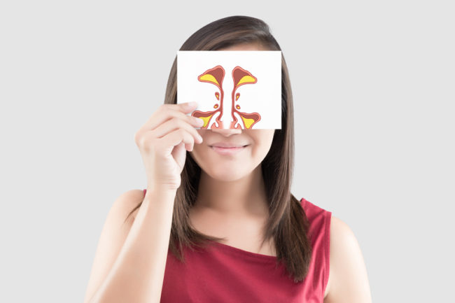 Smiling woman holding a picture of a sinus to her face