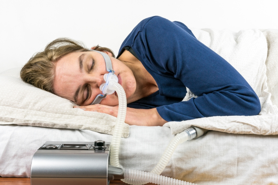 A woman with sleep apnea wearing a maks to help her sleep