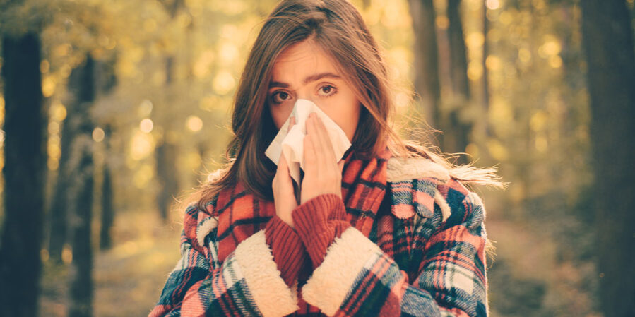 A young woman blowing her nose while outside