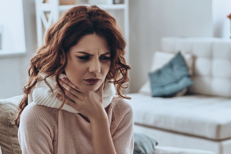 A woman suffering from a sore throat and sinus pain