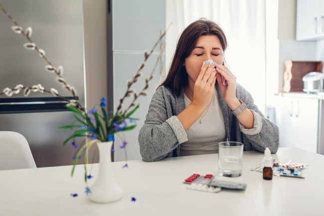 Spring Allergy. Young Woman Sneezing Because Of Flowers Surround