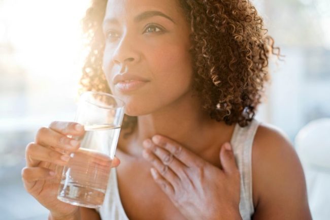 Woman drinking a glass of water mouth is dry